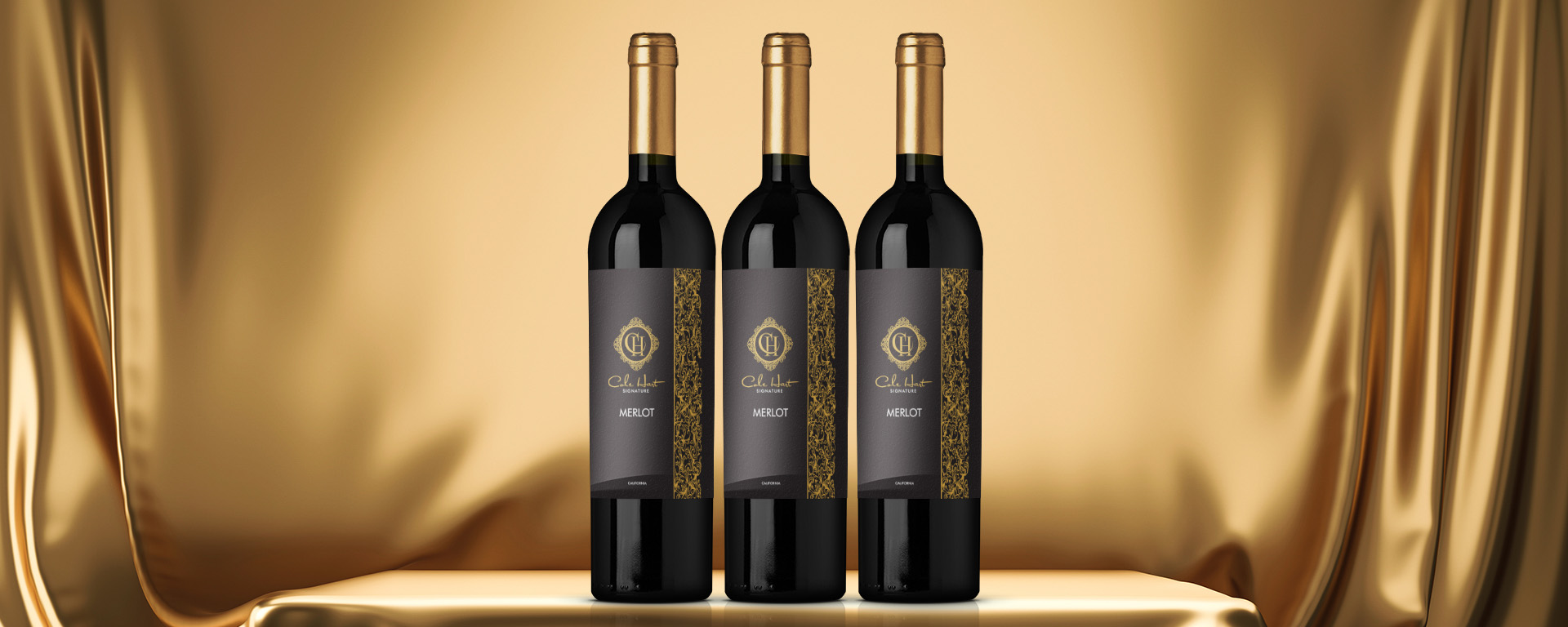 Three bottles of Cole Hart Signature Merlot in Front of Gold Backdrop