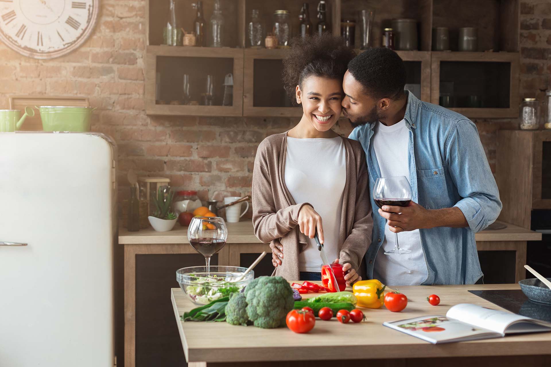 Beautiful girl cooking while her boyfriend kissing her in cheek